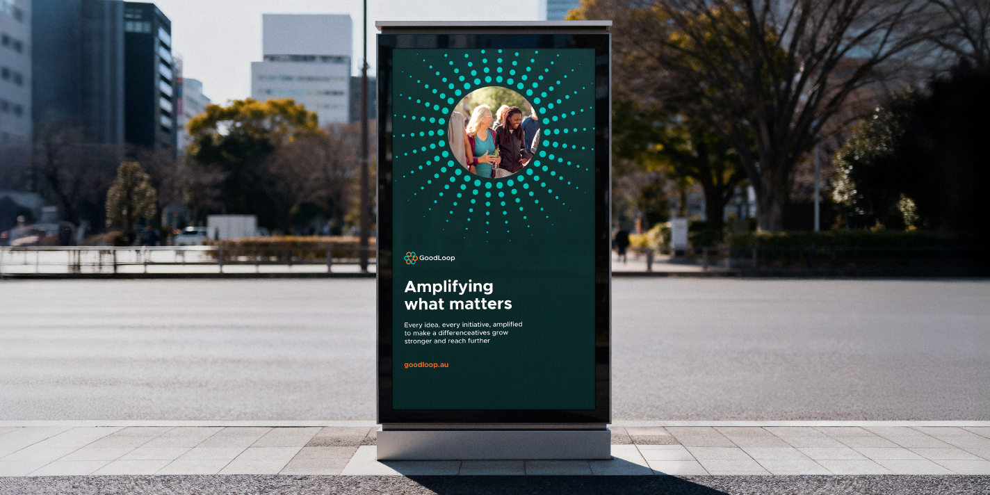 A vertical digital billboard on the curb of an urban road, with GoodLoop branding.