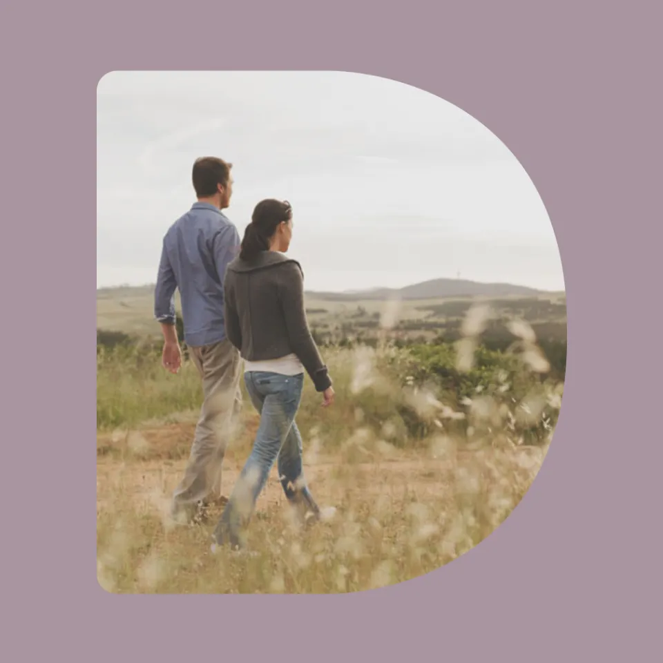 Two people walking in a field.